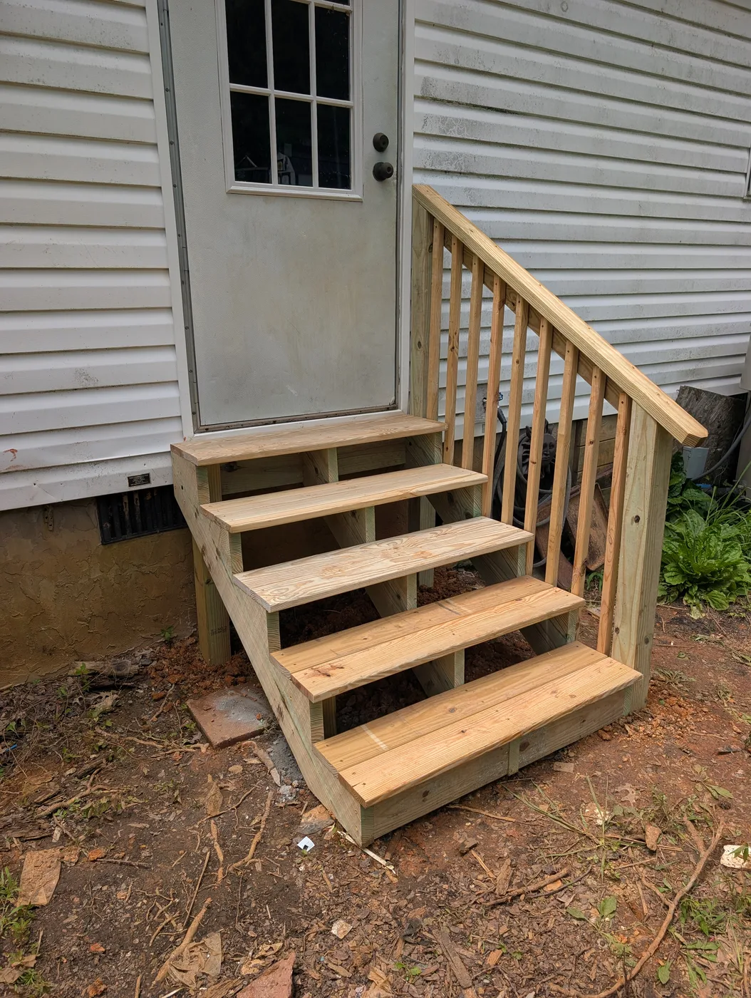Compact wood steps and handrail at a back door, completed by Frye Inc.