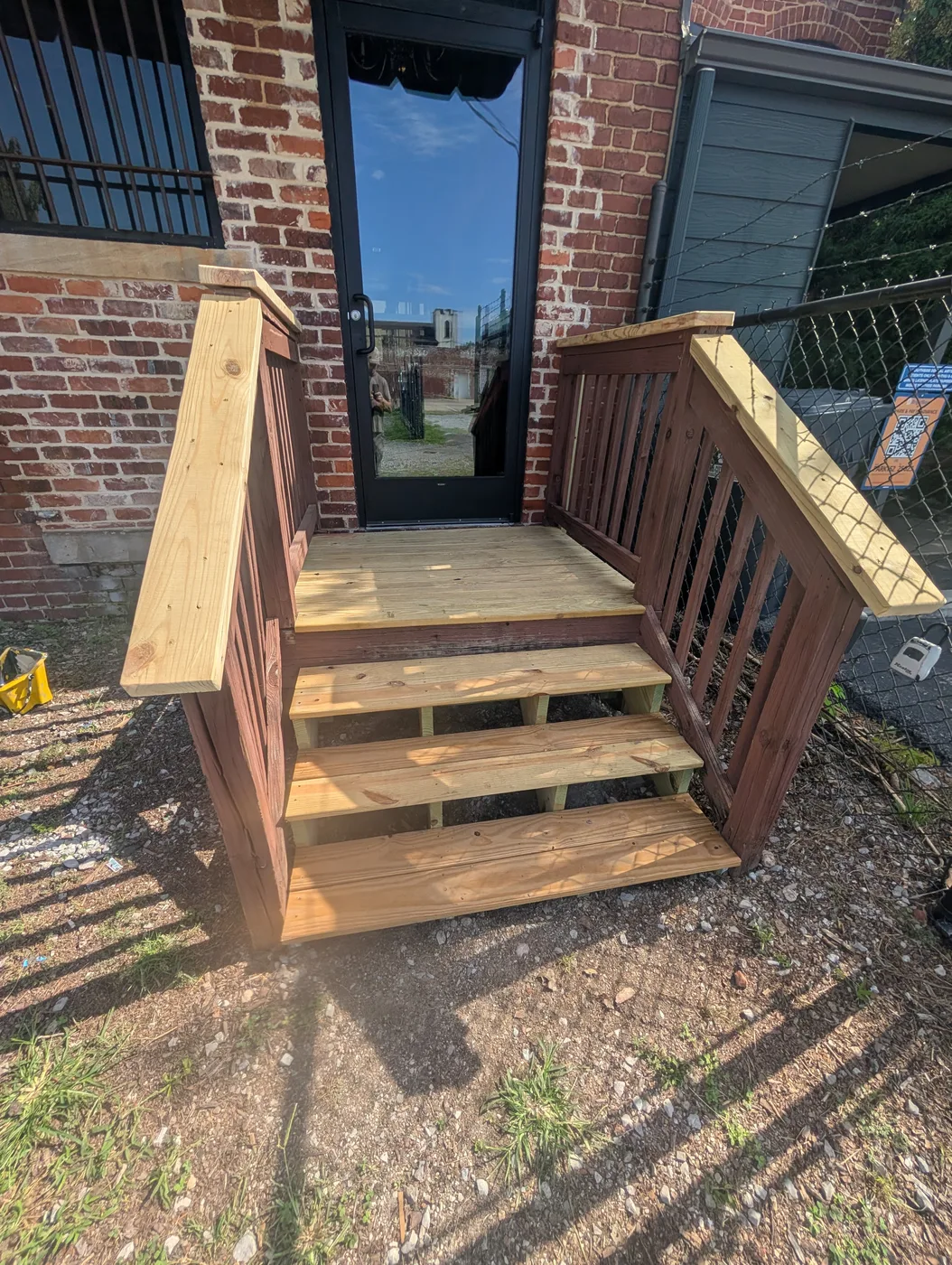 Wood entrance steps and handrails beside a brick wall, completed by Frye Inc.